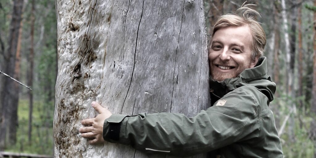 Professor of Disturbance Ecology Tuomas Aakala hugging a kelo-tree