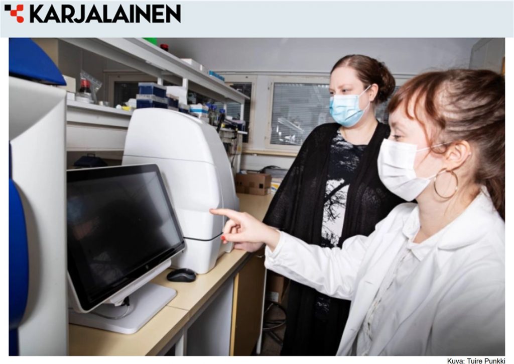 Two women at a computer in the laboratory, Karjalainen logo in the corner
