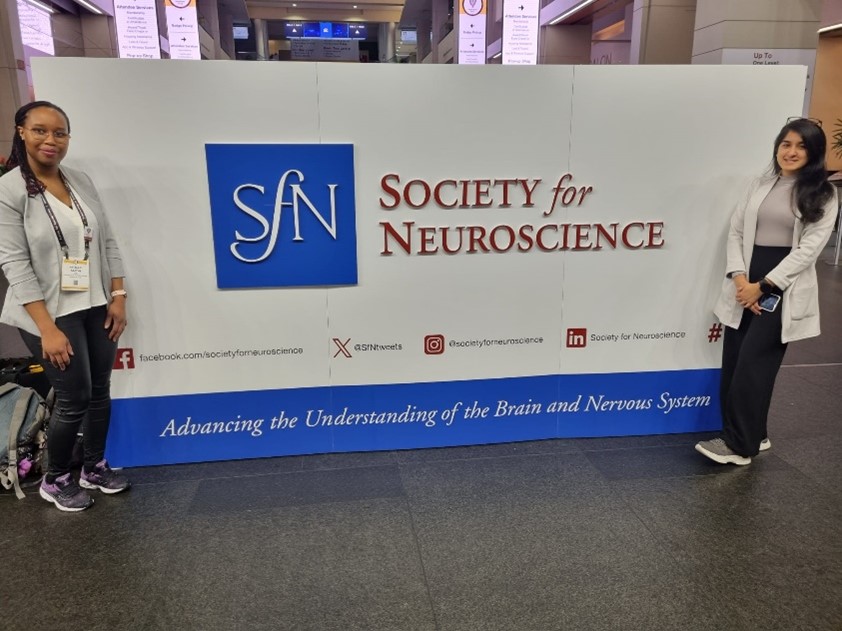 Picture of Meheli Banerjee and colleague in front of SFN conference banner.